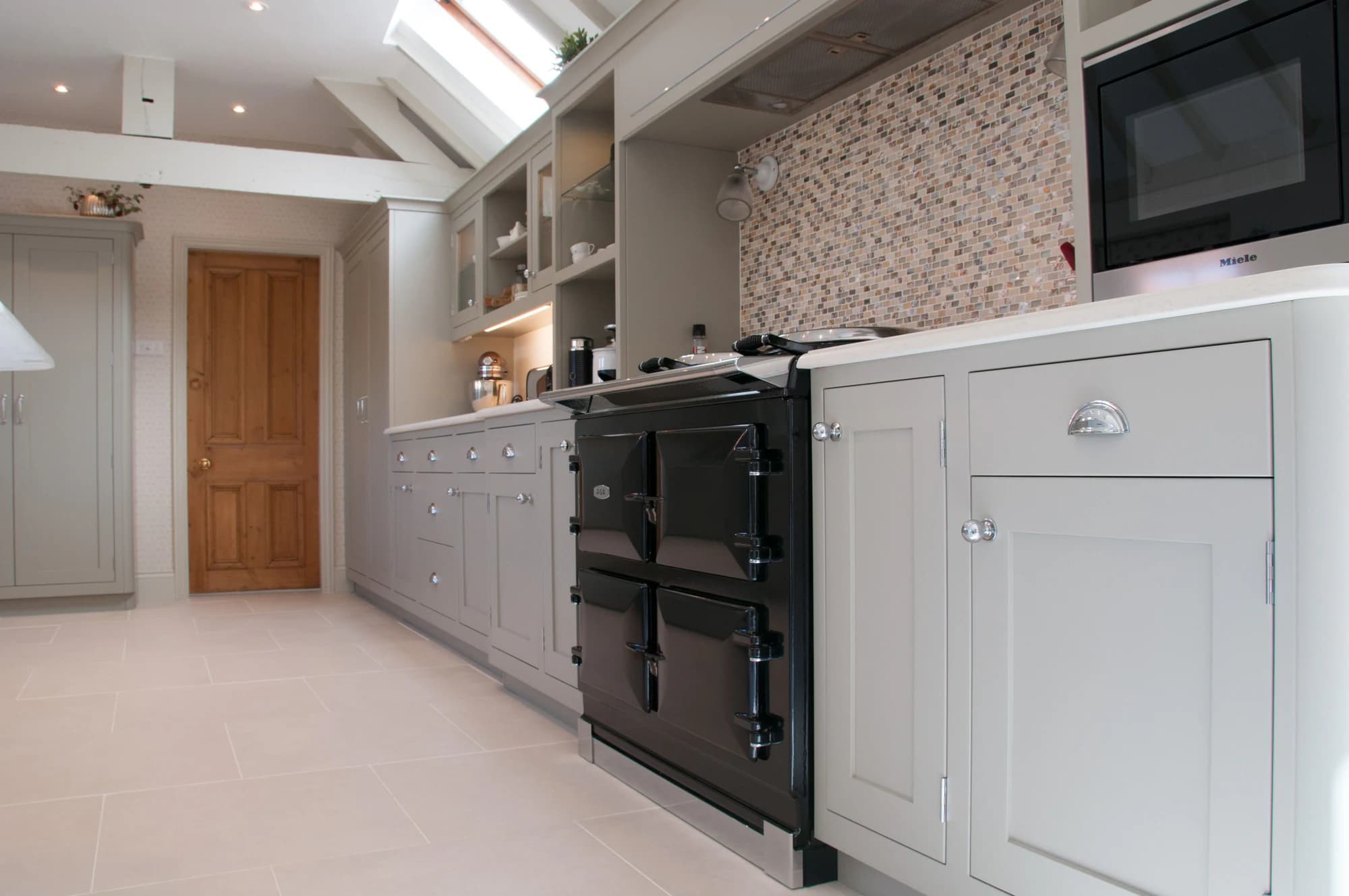 Painted shaker cabinets framing a black Aga beneath exposed beams