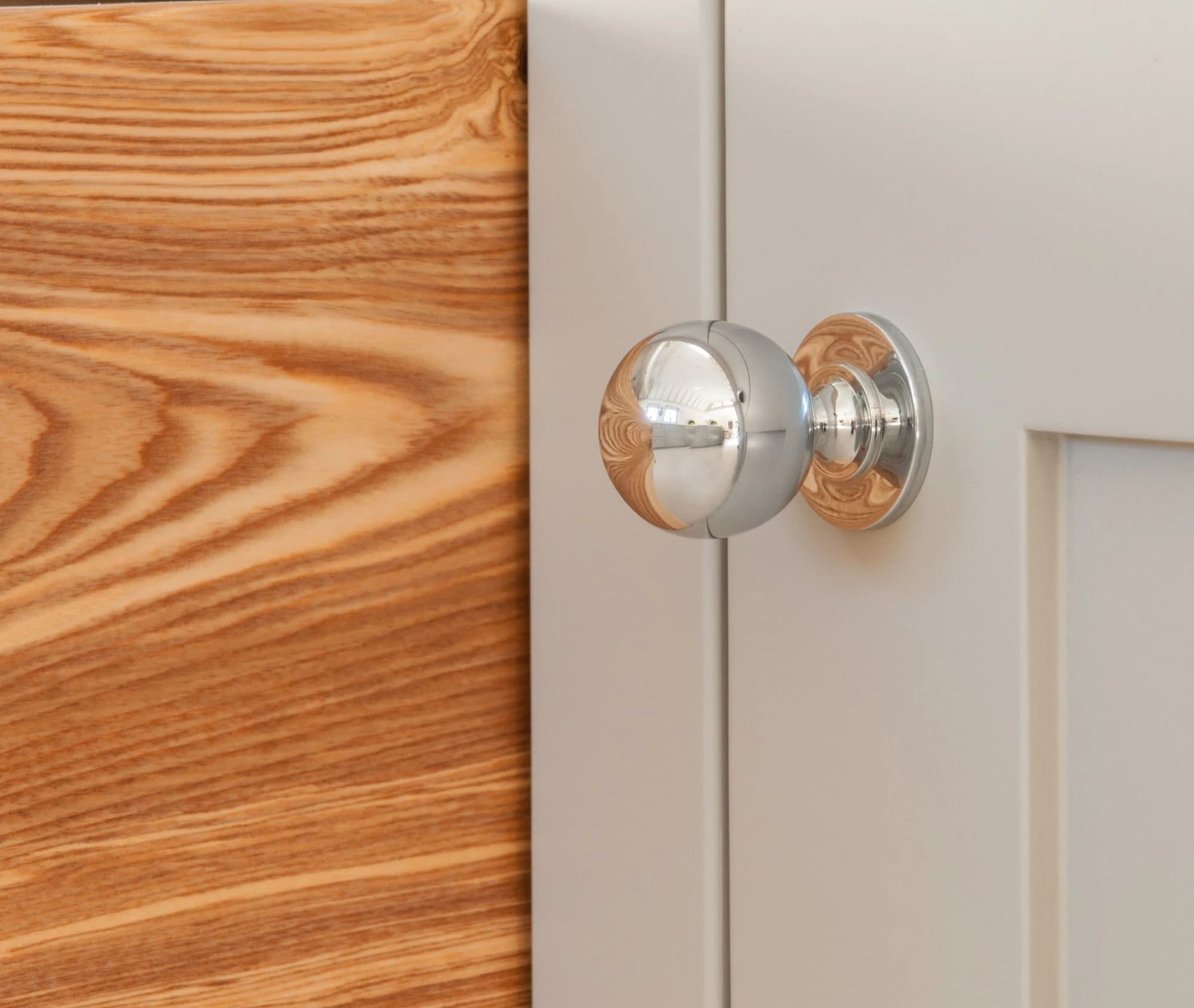 Polished cabinet knob beside a warm timber door