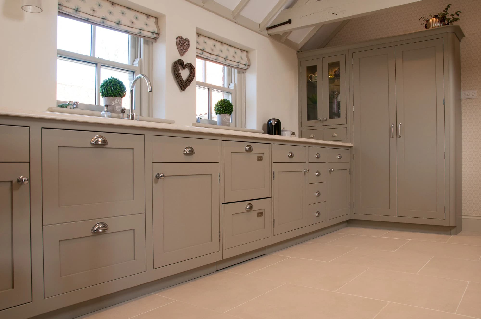 Long bank of shaker drawers and cabinets beneath two windows