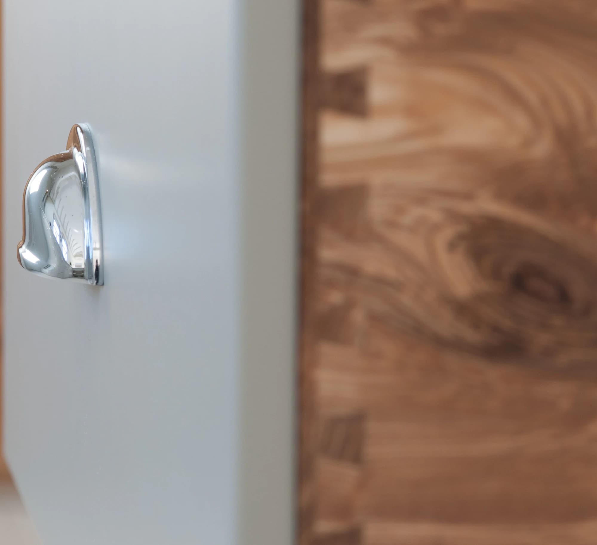 Close detail of a polished cup handle and painted drawer front
