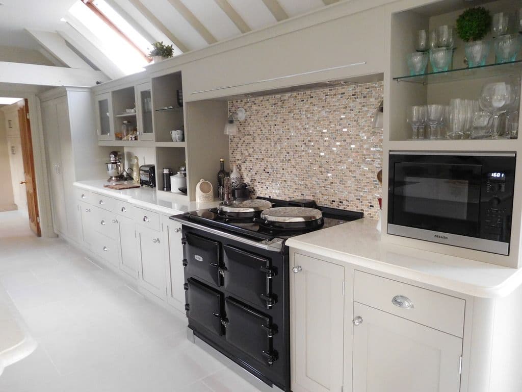 Black Aga framed by painted cabinetry and a mosaic splashback