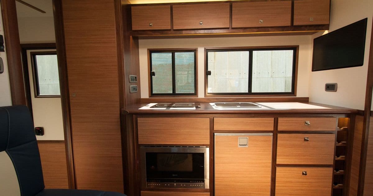 Full-width fitted kitchen and overhead storage in the horsebox interior