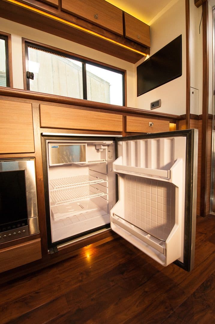 Open integrated refrigerator set within the horsebox timber cabinetry