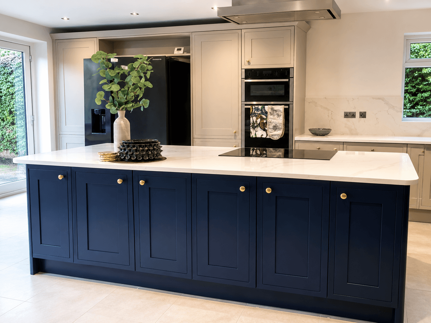 Ink-blue shaker kitchen island with brass knobs and a pale worktop